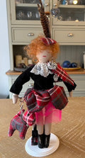 Handmade tartan doll homage to Vivienne Westwood, wearing a feathered hat and lace collar with a tartan bag